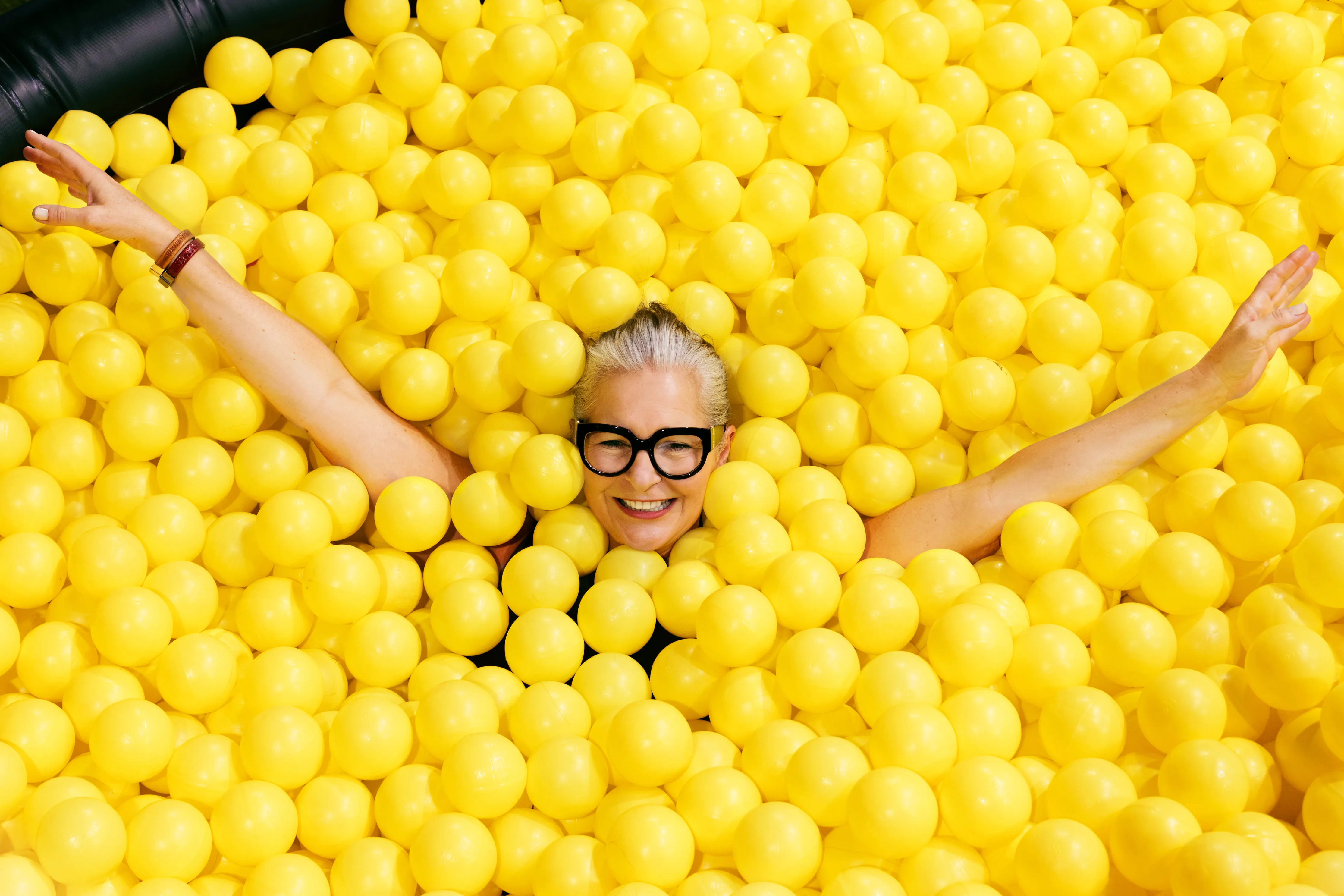 happy lady within a pool of yellow balls